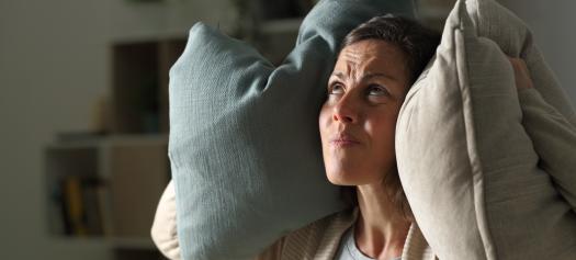 Volwassen vrouw geïrriteerd door het lawaai van haar buren bij haar thuis