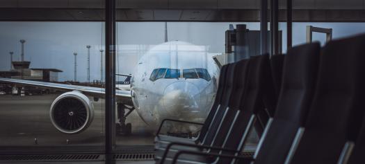 Vliegtuig geparkeerd op een luchthaven, gezien door het raam van de boarding gate.