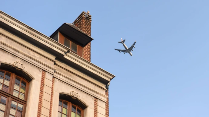 Un avion vole au-dessus d un bâtiment dans un ciel bleu
