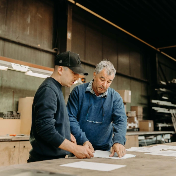 Deux hommes dans un atelier analysent des plans sur papier
