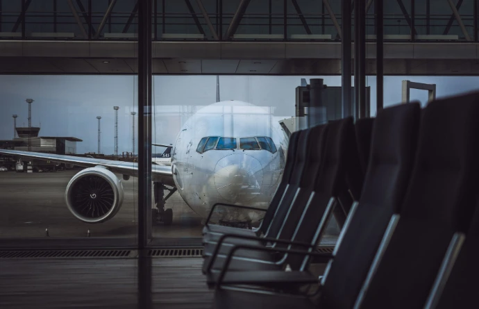 Avion stationné dans un aéroport, vu à travers la vitre de la porte d'embarquement.