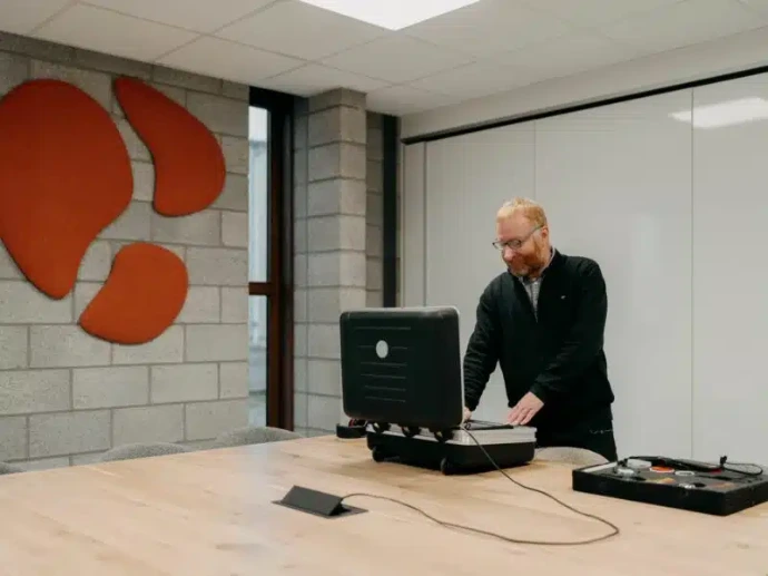 Un homme debout à une table avec un ordinateur portable