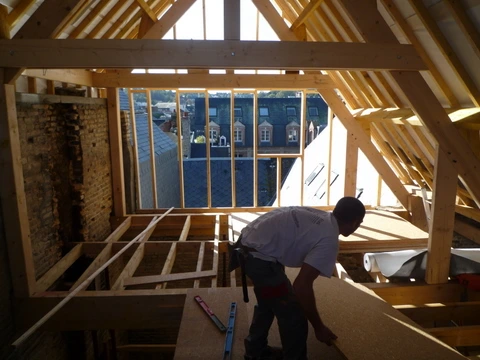 Un homme travaille dans une maison en ossature bois en construction