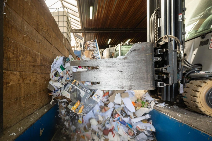 Une machine dépose du papier carton dans une benne