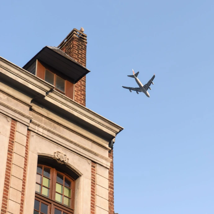 Un avion vole au-dessus d un bâtiment dans un ciel bleu